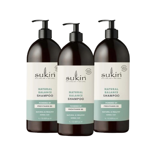 A bottle of Sukin Natural Balance Shampoo for normal hair displayed on a clean, white marble surface with botanical leaves in the background.