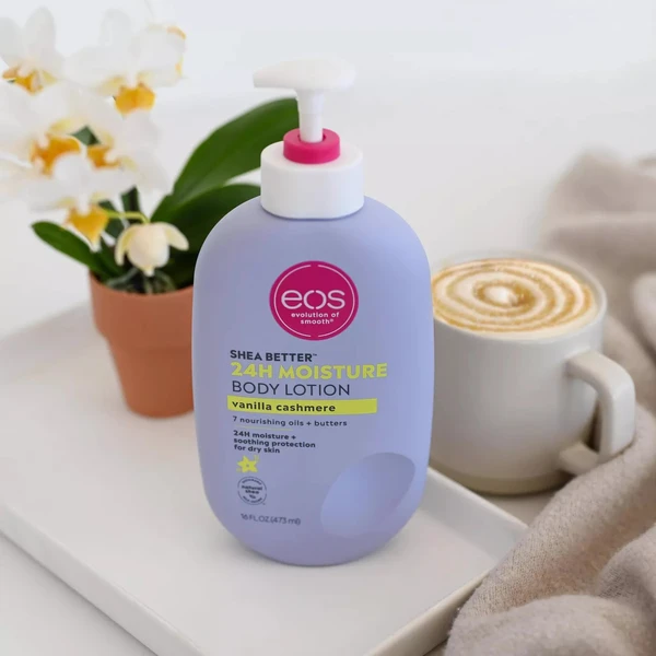 EOS Shea Better 24H Moisture Body Lotion in Vanilla Cashmere on a white tray with a coffee cup and white orchids.