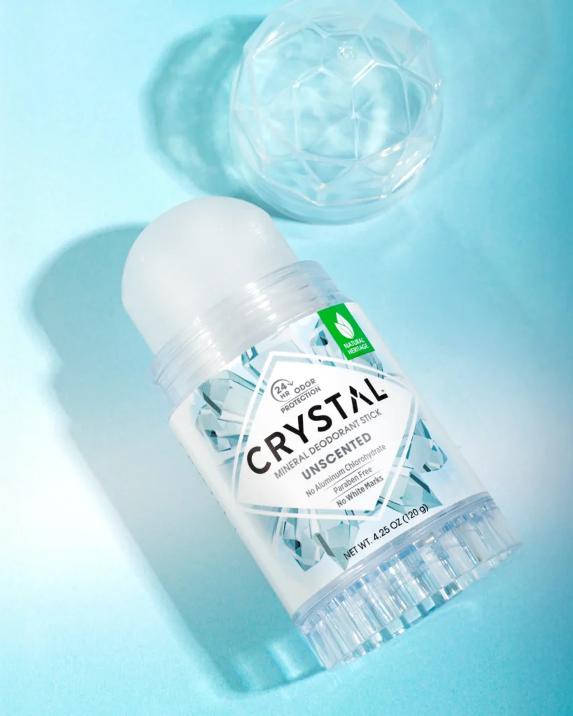 A 120g CRYSTAL mineral deodorant stick unscented sitting on a bathroom counter, showcasing its clear natural salt stone texture